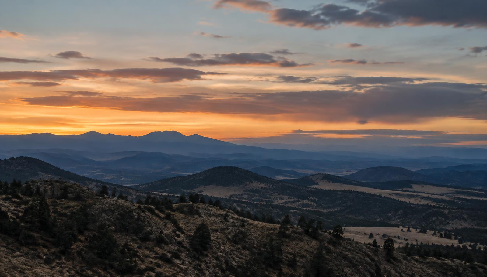 Colorado foothills at dusk with a low band of warm light at the horizon